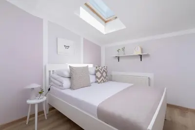 a white bedroom with a bed and a skylight at 3-Bedroom apartment in the centre - Old Town in Kraków