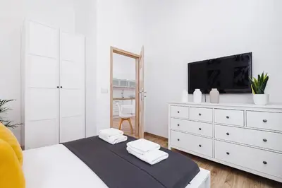a white bedroom with a tv and a white dresser at Two-bedroom apartment - Old Town in Kraków
