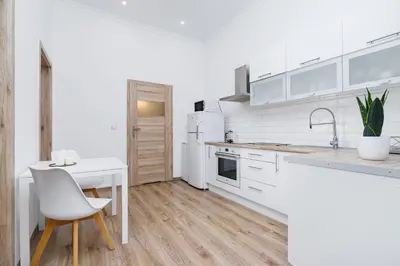 a white kitchen with a table and a white chair at Two-bedroom apartment - Old Town in Kraków