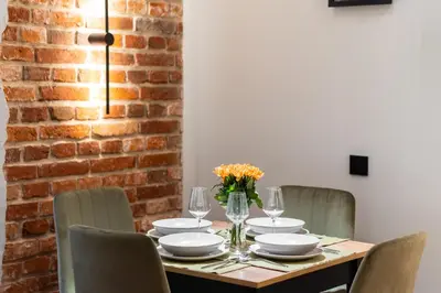 a dining room table with chairs and a brick wall at Charm & Comfort Renovated Gem in Old Town Sarego apt B in Kraków