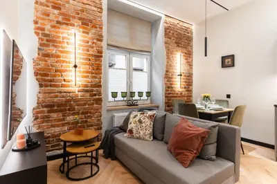 a living room with a couch and a brick wall at Charm & Comfort Renovated Gem in Old Town Sarego apt B in Kraków