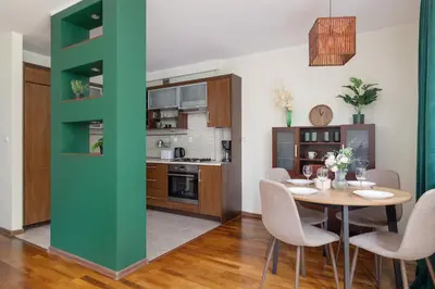a kitchen and dining room with a table and chairs at Cracow Verdant Apartment with Parking by Noclegi Renters in Kraków