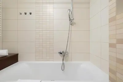 a bathroom with a shower with white tiles at Cracow Verdant Apartment with Parking by Noclegi Renters in Kraków
