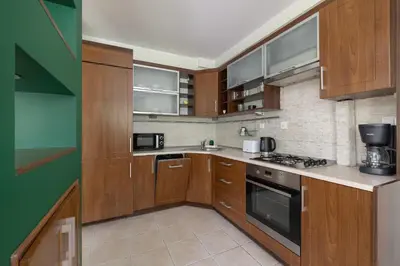 a kitchen with wooden cabinets and a stove at Cracow Verdant Apartment with Parking by Noclegi Renters in Kraków