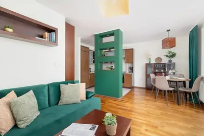 a living room with a green couch and a table at Cracow Verdant Apartment with Parking by Noclegi Renters in Kraków