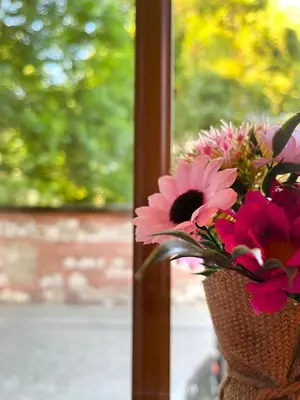 a vase filled with pink flowers in a window at Large Apartment 2 bedrooms and living room, Kazimierz District in Kraków