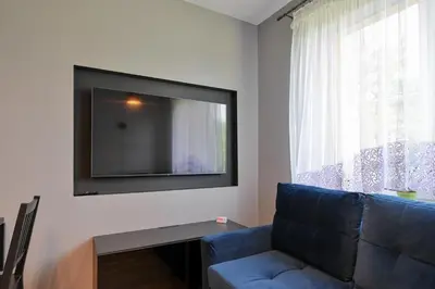a living room with a blue couch and a flat screen tv at RentPlanet - Apartament Kasztelańska in Kraków