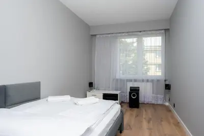 two beds in a white room with a window at RentPlanet - Apartament Kasztelańska in Kraków