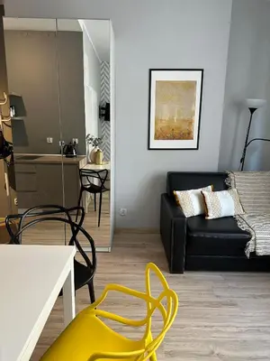 a living room with a black couch and a yellow chair at Apartament Mazowiecka 11 in Kraków