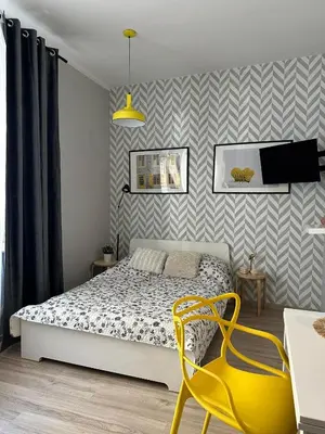 a bedroom with a bed and a yellow chair at Apartament Mazowiecka 11 in Kraków