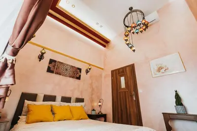 a bedroom with a bed with yellow pillows and a chandelier at Apartament Shahrazad in Kraków