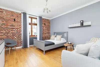 a living room with a bed and a brick wall at Two Bedroom Apartment- Brzozowa - Kazimierz in Kraków