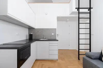 a kitchen with white cabinets and a black counter top at Old Town - Modern Apartment - 7 Gertrudy street in Kraków