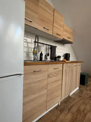 a kitchen with wooden cabinets and a white refrigerator at Moonlight Apartment Cracow in Kraków