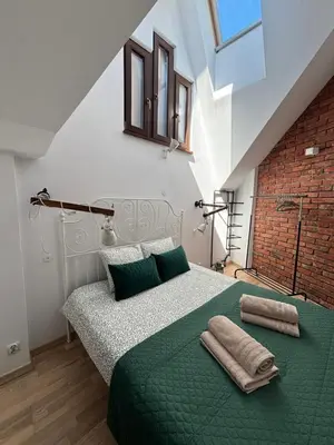 a bedroom with a green bed with a brick wall at Moonlight Apartment Cracow in Kraków
