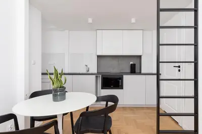 a white kitchen with a white table and chairs at Wawel Castle - Modern Apartment - 7 Gertrudy in Kraków