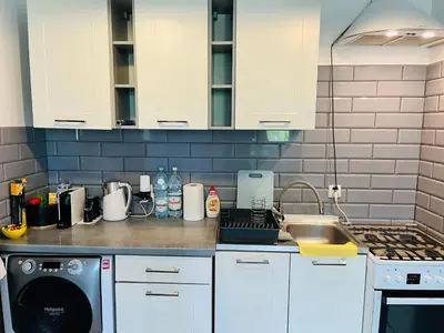 a kitchen with white cabinets and a sink at Apartament ogrodowy in Miechów