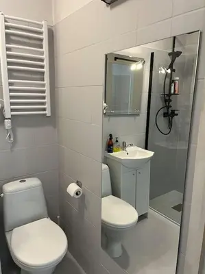 a white bathroom with a toilet and a sink at Apartament ogrodowy in Miechów