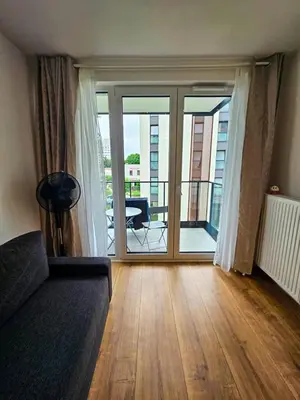 a living room with a couch and a sliding glass door at Elegant Two-Room Apartment, Sleeps 4, Near Turon Arena, Balcony ,Air condition in Kraków