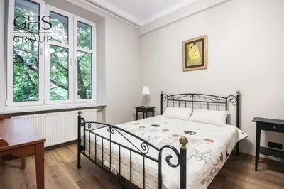 a bedroom with a bed and a desk and windows at Royal university apartment, Wawel castle in Kraków
