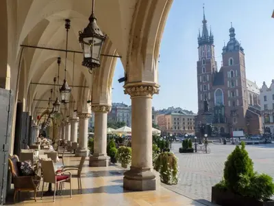 a building with an arch with tables and chairs at Royal university apartment, Wawel castle in Kraków