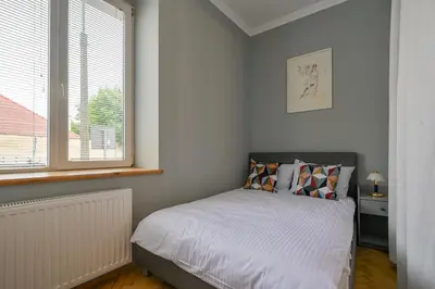 a small bedroom with a bed and a window at Krowoderska Apartament in Kraków