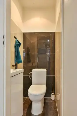 a bathroom with a white toilet and a sink at Krowoderska Apartament in Kraków