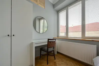 a room with a chair and a mirror and windows at Krowoderska Apartament in Kraków