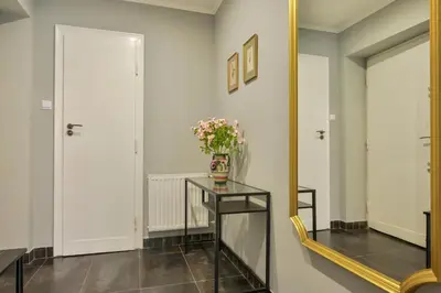 a hallway with a mirror and a table with flowers on it at Krowoderska Apartament in Kraków