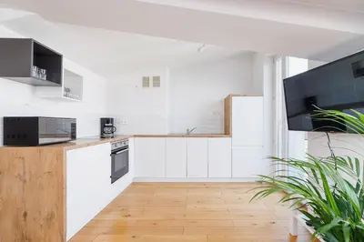 a kitchen with white cabinets and a wooden floor at 2 bedroom Apartment with terrace- Piłsudskiego 11 in Kraków