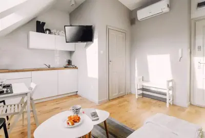 a white living room with a table and a kitchen at 1 - bedroom Apartment - 11 Pilsudskiego Street in Kraków