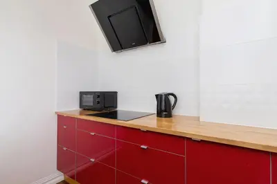 a kitchen with red cabinets and a tv on the wall at Main square - Old Town - Floriańska 47 Street in Kraków