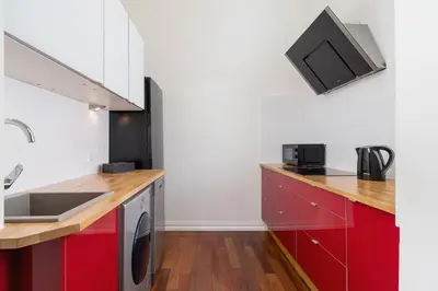 a kitchen with red cabinets and a tv on the wall at Main square - Old Town - Floriańska 47 Street in Kraków
