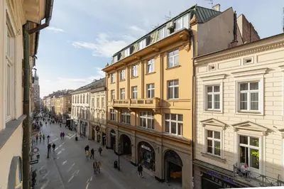 a group of people walking down a street with buildings at Main square - Old Town - Floriańska 47 Street in Kraków