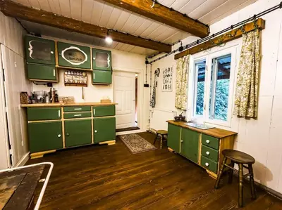 a kitchen with green cabinets and a desk and a window at Grapa - Magiczna Leśna Chata in Skawica