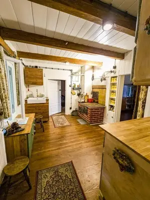 a large kitchen with wooden floors and a counter top at Grapa - Magiczna Leśna Chata in Skawica