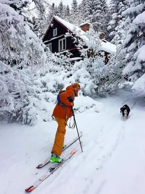 a man on skis in the snow with a dog at Grapa - Magiczna Leśna Chata in Skawica