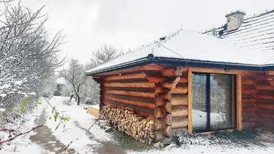 a log cabin in the snow with a window at Pod lasem i niebem in Lanckorona