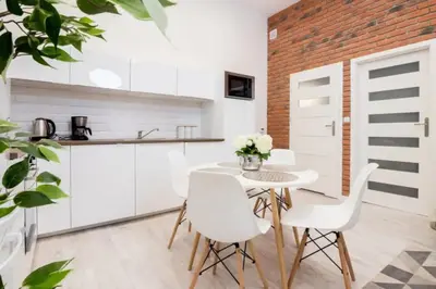 a kitchen with white cabinets and a table and chairs at One Bedroom Apartment - Dluga 30 street in Kraków