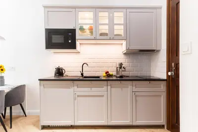 a kitchen with white cabinets and a black counter top at Vintage Charm in Old Town Krakow Józefa Sarego apt A in Kraków