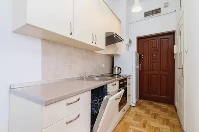 a kitchen with white cabinets and a sink and a door at Private Parking - Old Town - Św Krzyża 16 Street in Kraków