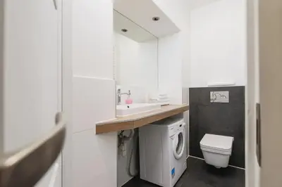a bathroom with a sink and a washing machine at Private Parking - Old Town - Św Krzyża 16 Street in Kraków
