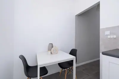 a white table and two black chairs in a kitchen at 2-Bedroom Apartment With Balcony - Długa 65 street in Kraków