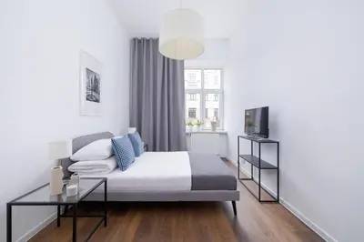 a bedroom with a bed and a table and a tv at 2-Bedroom Apartment With Balcony - Długa 65 street in Kraków