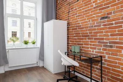 a brick wall with a white desk and a chair at 2-Bedroom Apartment - Długa 65 Street in Kraków