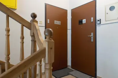 a brown door in a hallway with stairs at 2-Bedroom Apartment - Długa 65 Street in Kraków