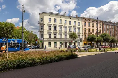 a large white building on a city street with a bus at 2-Bedroom Apartment - Długa 65 Street in Kraków