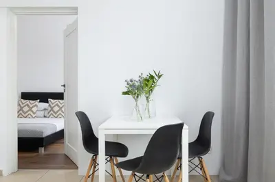 a dining room with a white table and black chairs at 2-Bedroom Apartment - Długa 65 Street in Kraków