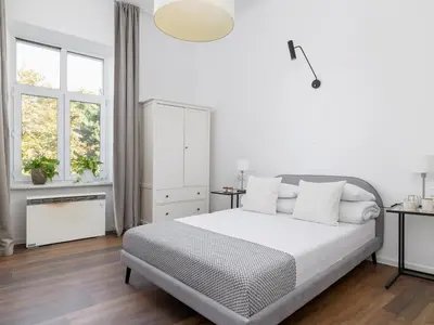 a white bedroom with a bed and two windows at 1-bedroom apartment - Długa 65 street in Kraków