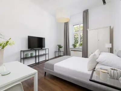 a white bedroom with a bed and a tv at 1-bedroom apartment - Długa 65 street in Kraków